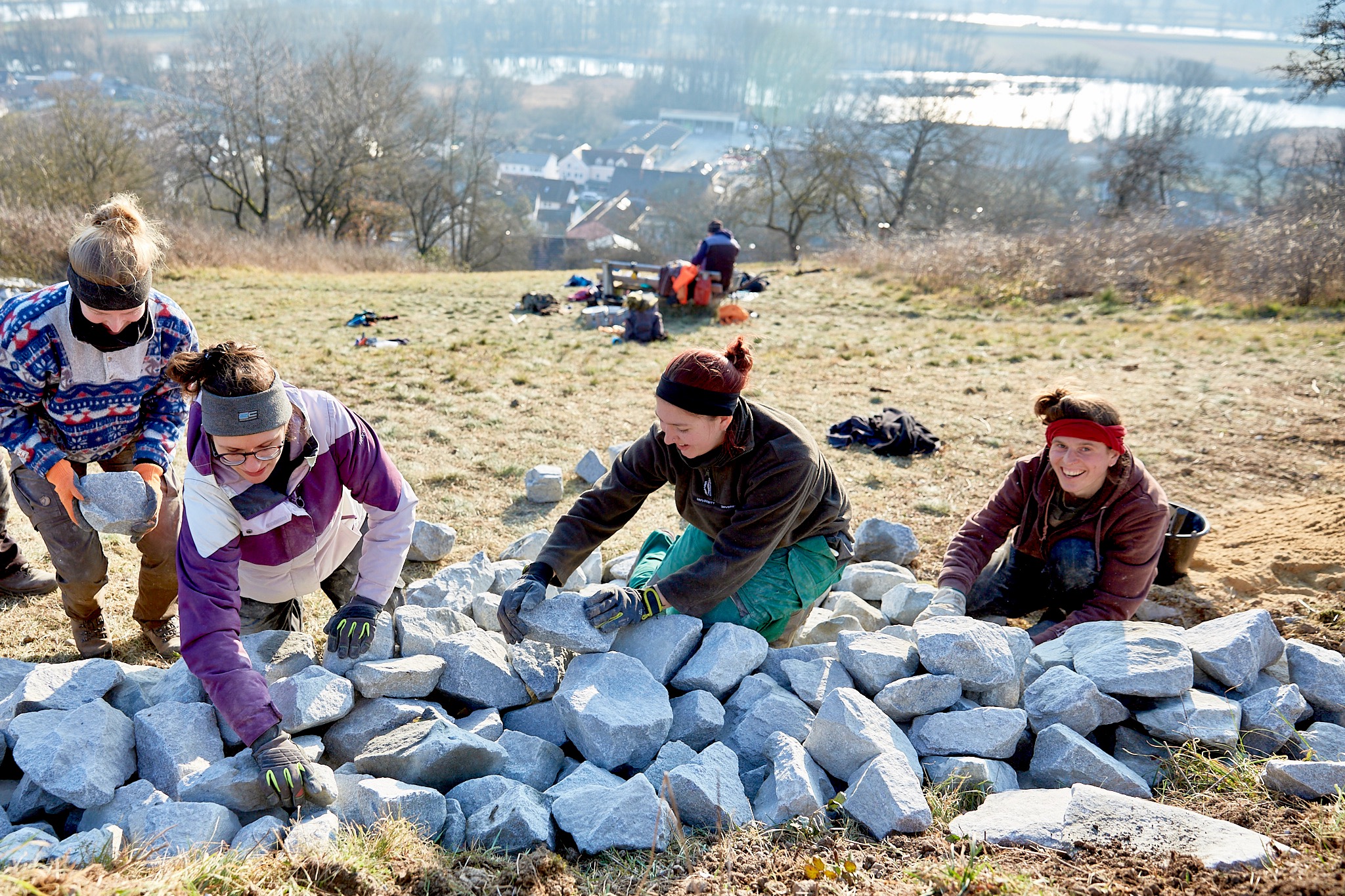 Vier Frauen beugen sich über einen Granitsteinhaufen