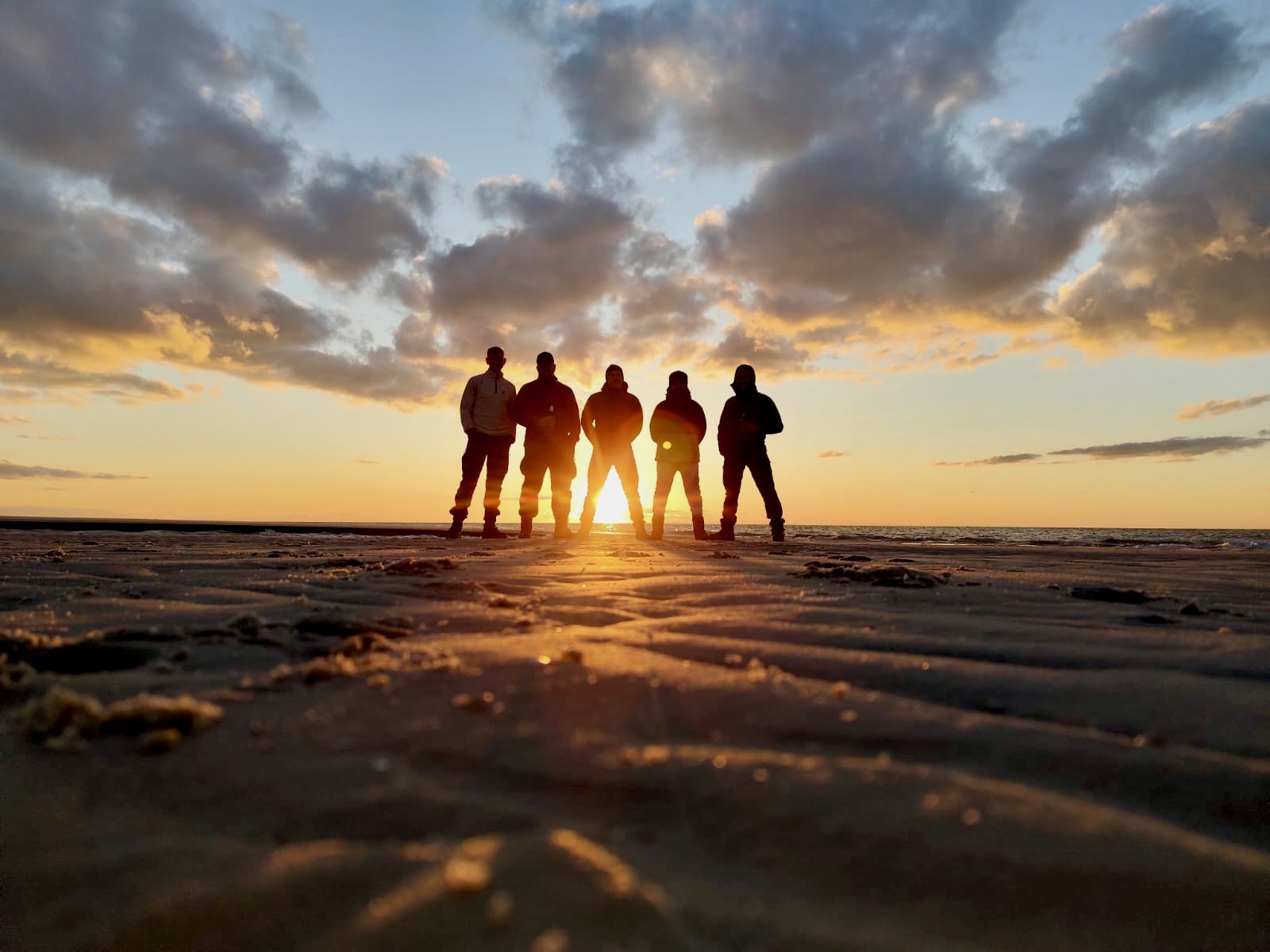 Kniepsandposing Fünf Menschen stehen vor dem Sonnenuntergang im Kniepsand