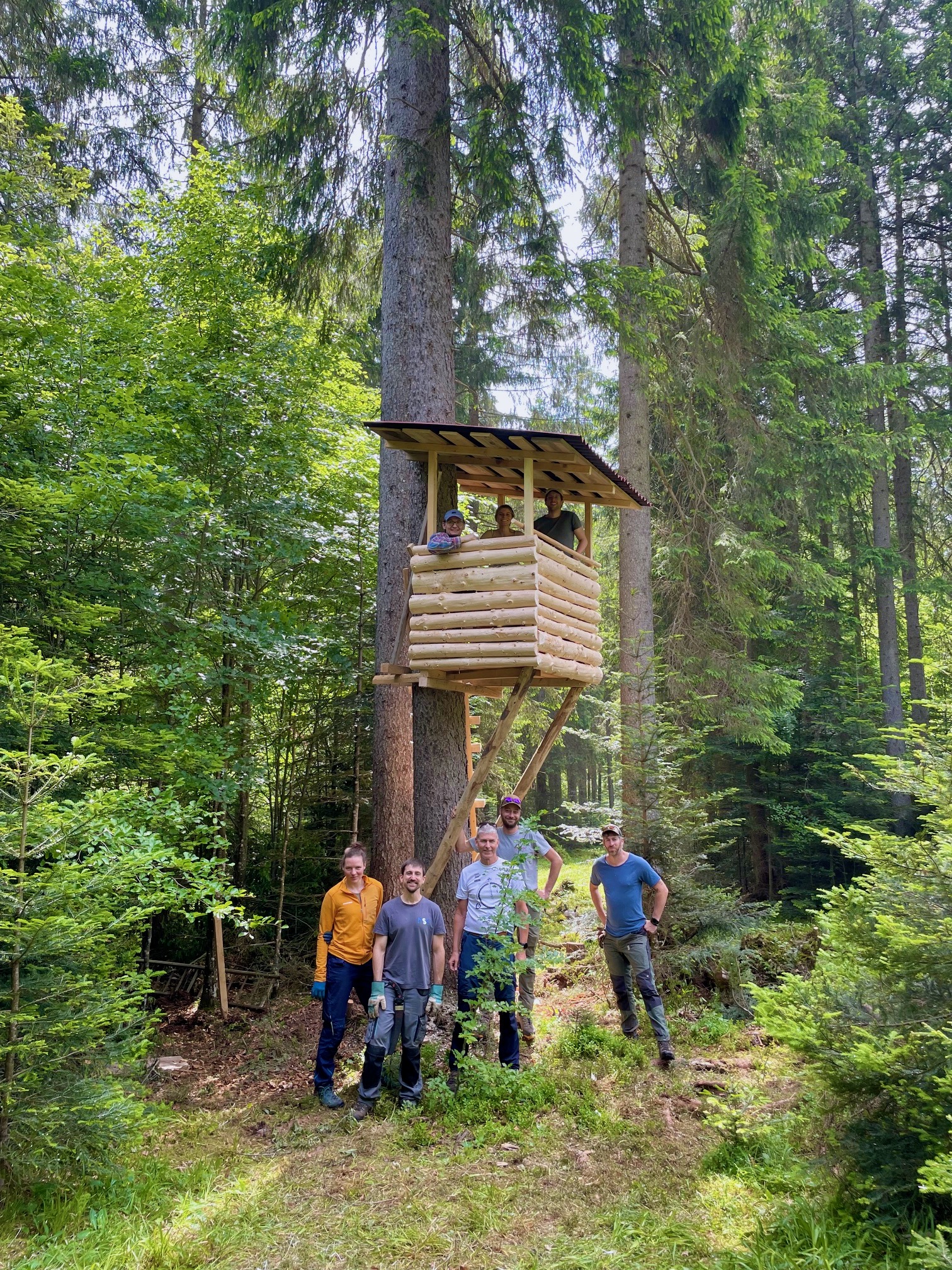 Gebaut für die Ewigkeit Menschen stehen vor einem Hochsitz, auf dem drei Menschen sitzen