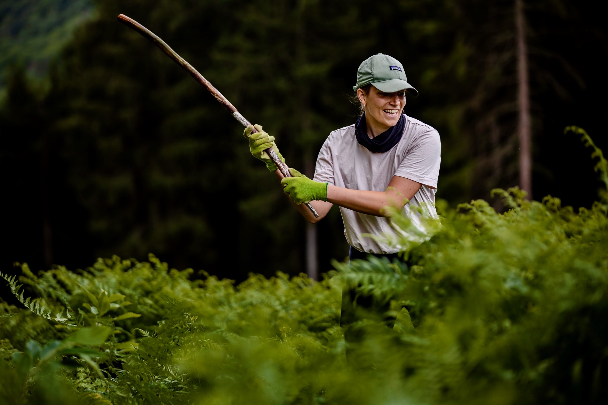 Frau holt mit einem langen Ast zum Schlag aus