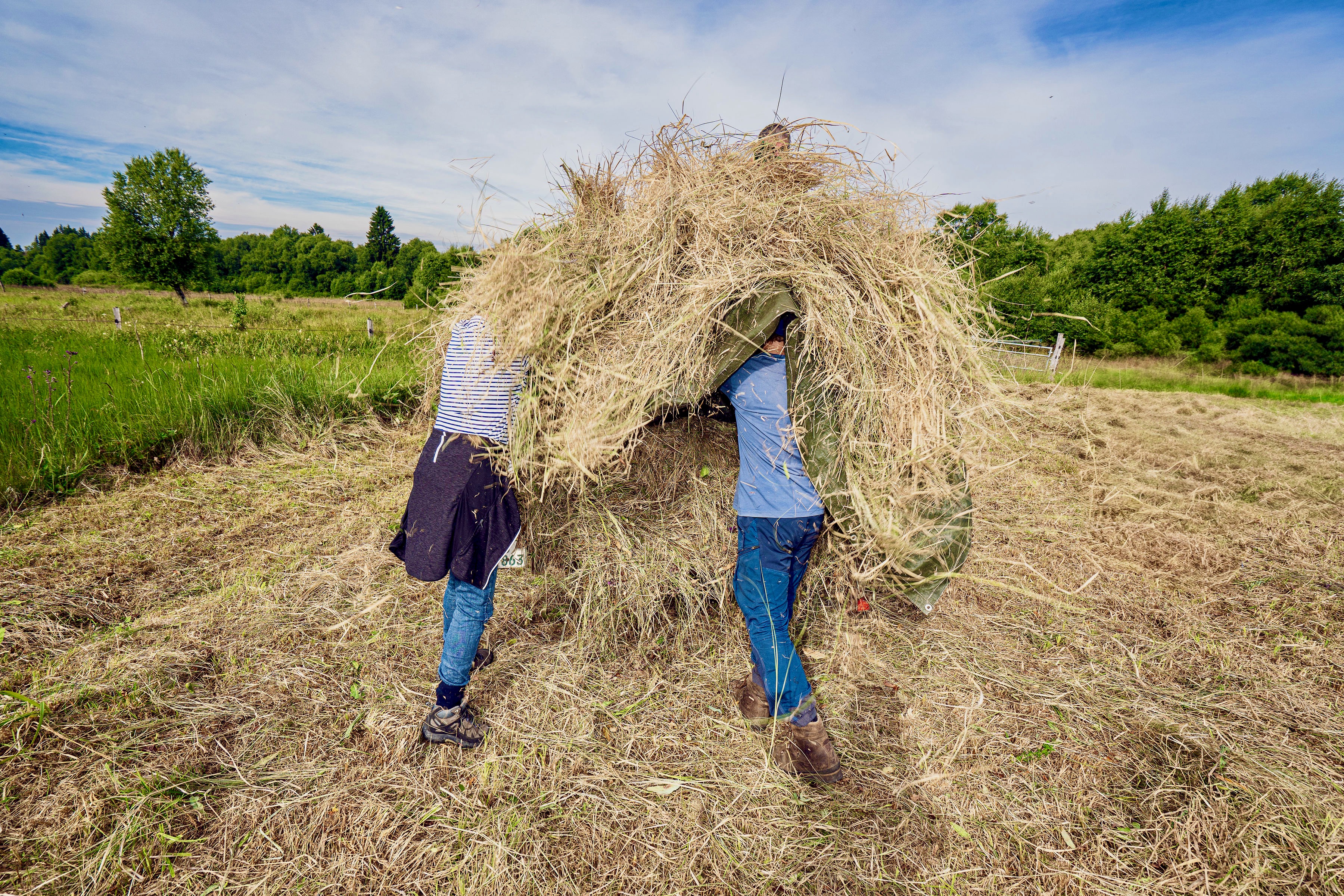 Heureka, die Nadel ist gefunden. Zwei Menschen stecken stehend im Heuschober