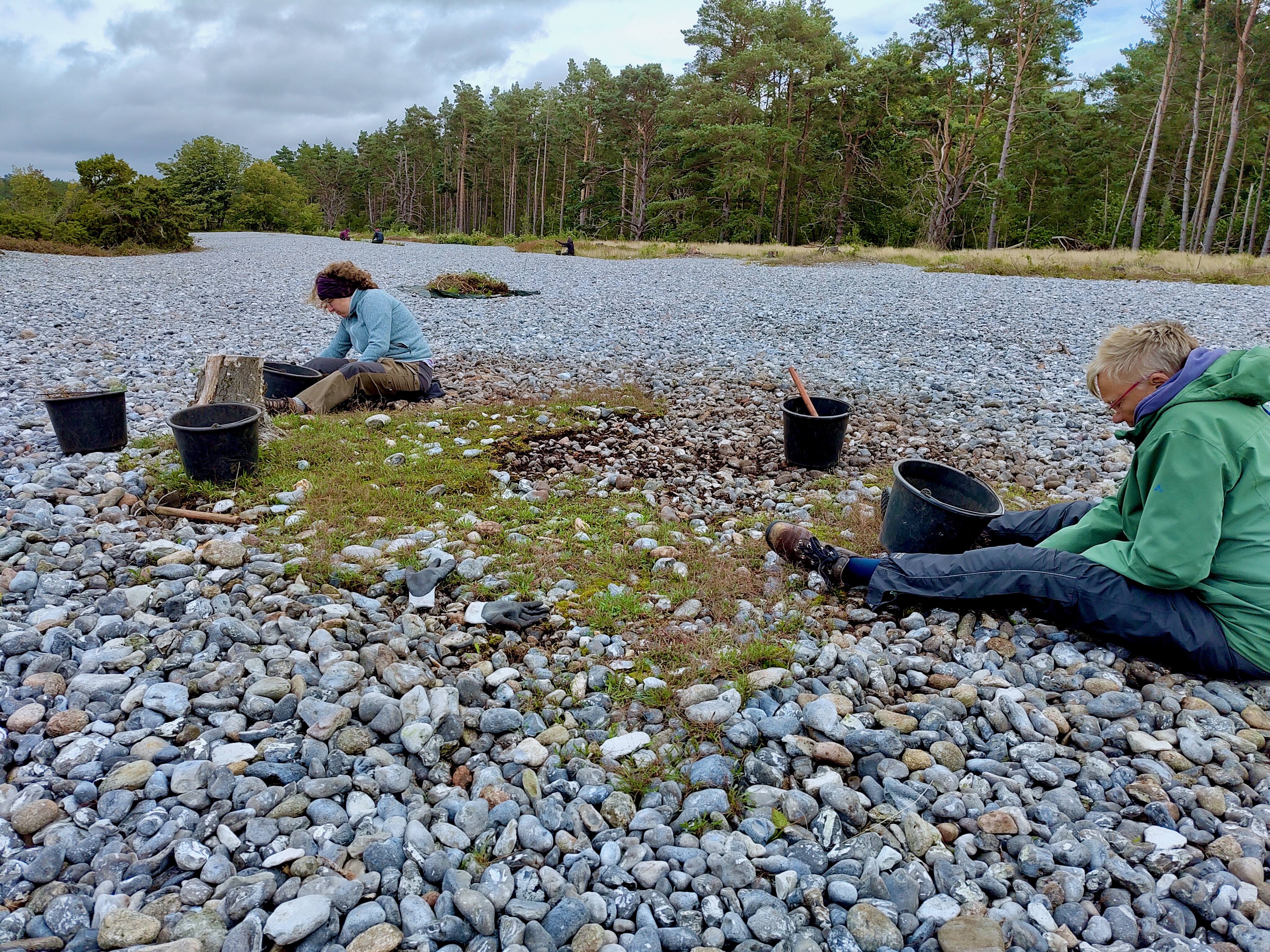 Zwei Frauen sitzen auf einer Kiesfläche, am Rande Hochwald