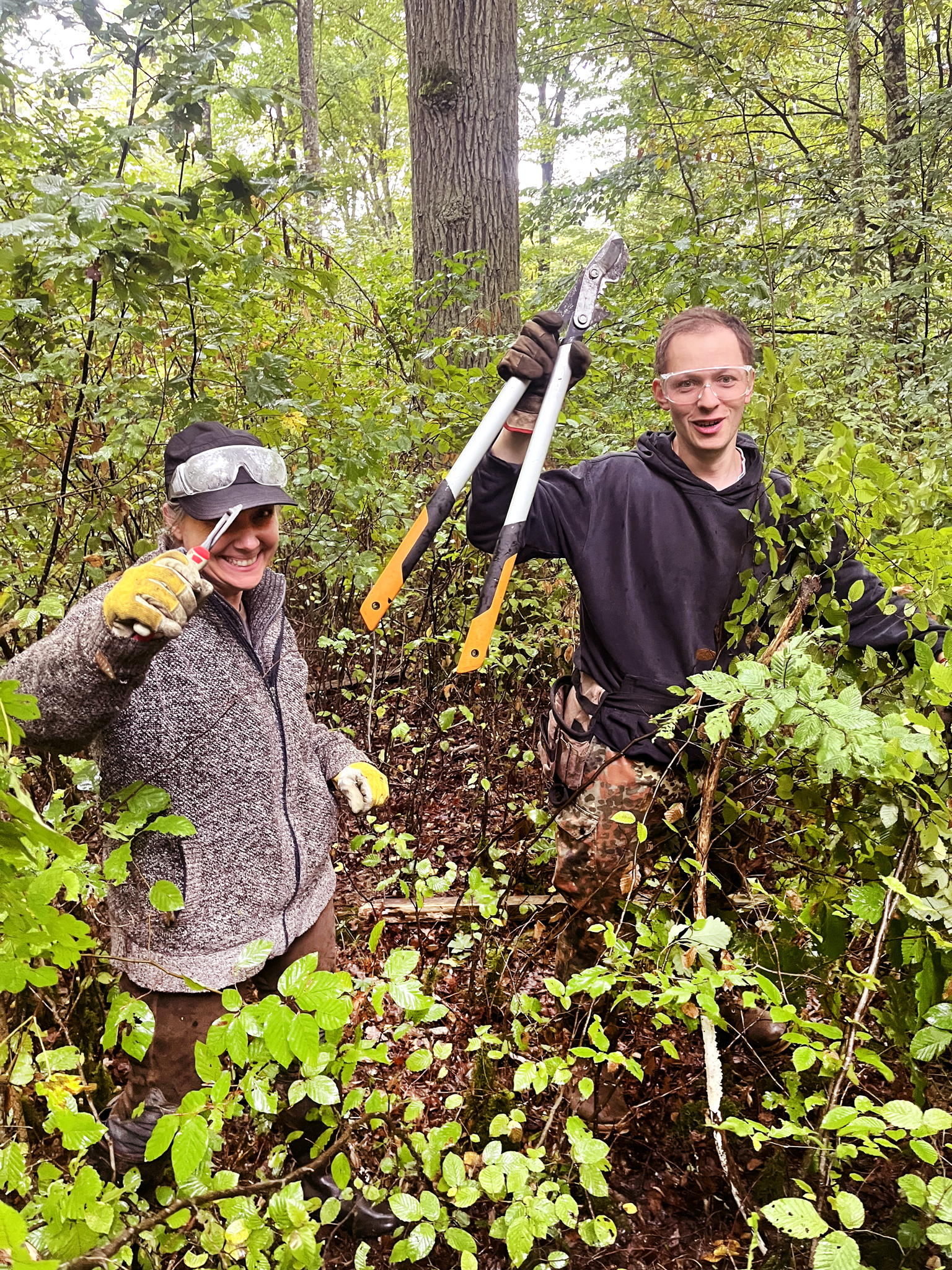 zwei Personen mit Werkzeug im Wald