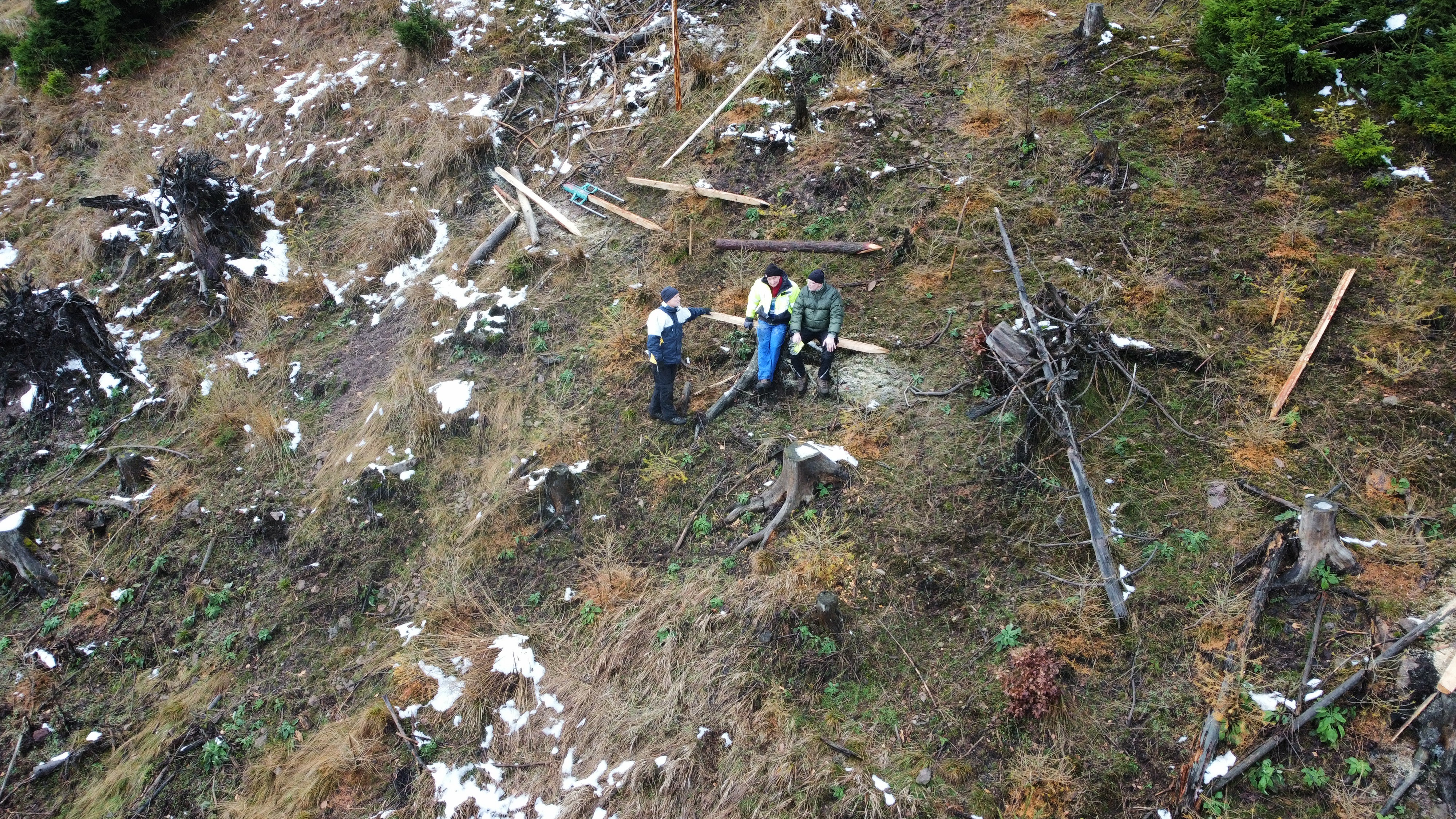 Drohnenaufnahme von drei Personen, die am Hang arbeiten