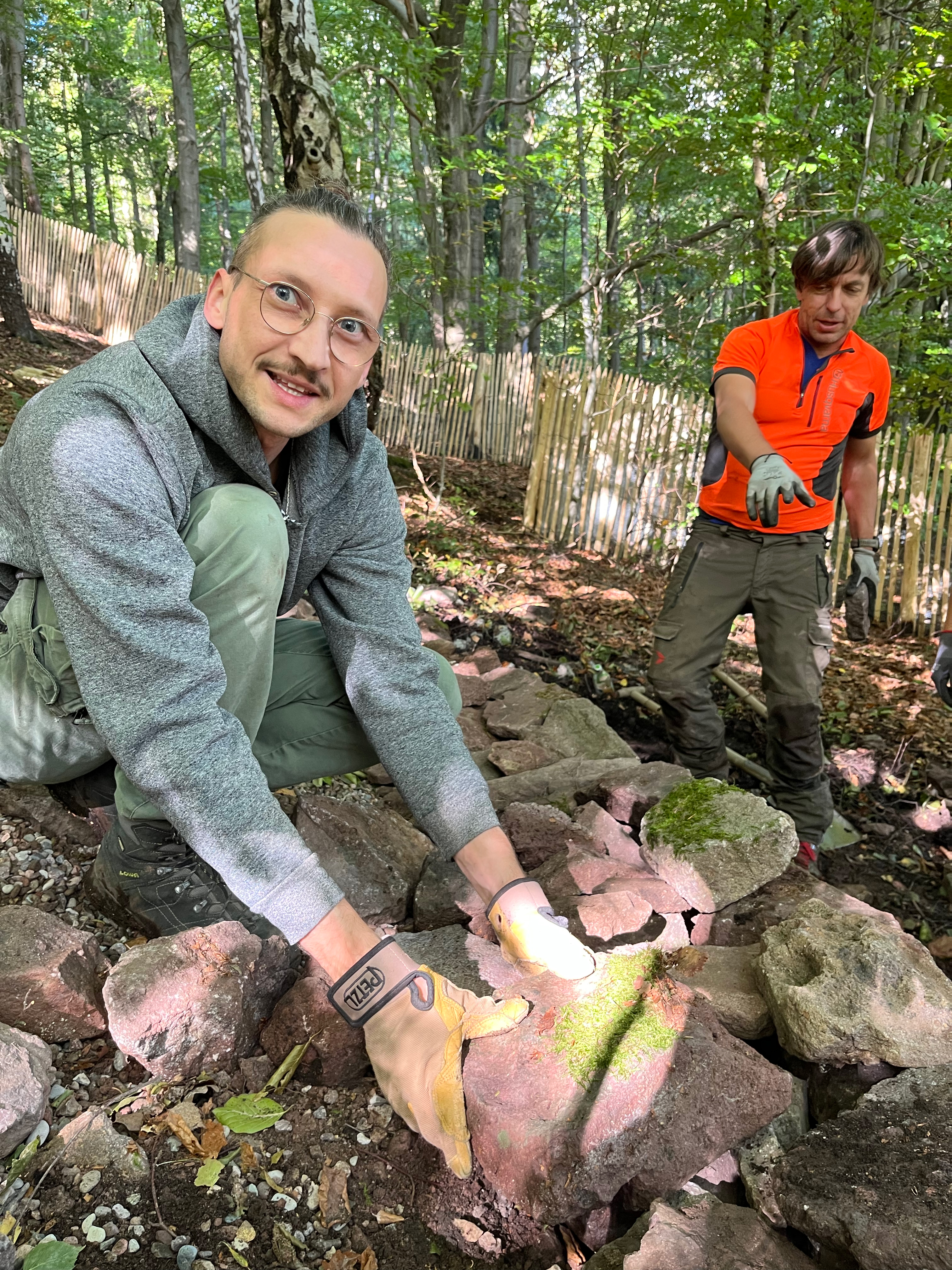 Person baut Trockensteinmauer