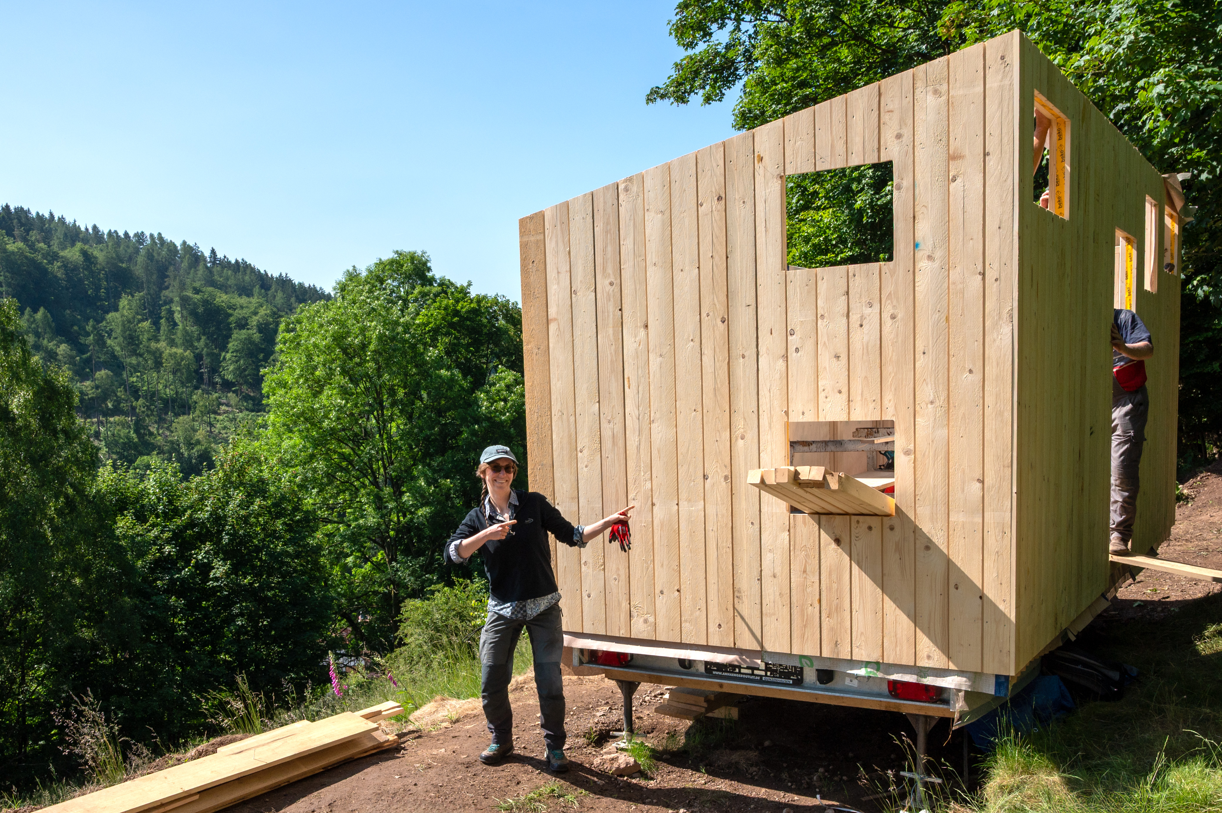 Person steht vor einem Bauwagen