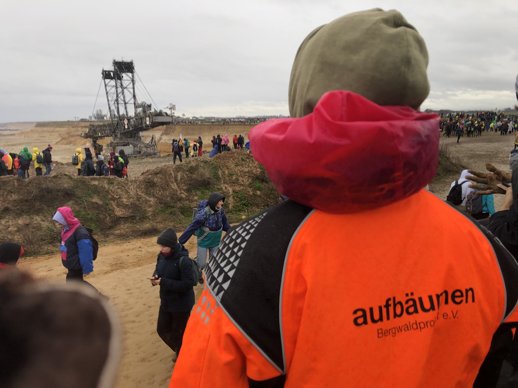 Mensch mit Jacke mit dem Schriftzug "Aufbäumen" steht an einem Tagebau Mensch mit Jacke mit dem Schriftzug "Aufbäumen" steht an einem Tagebau