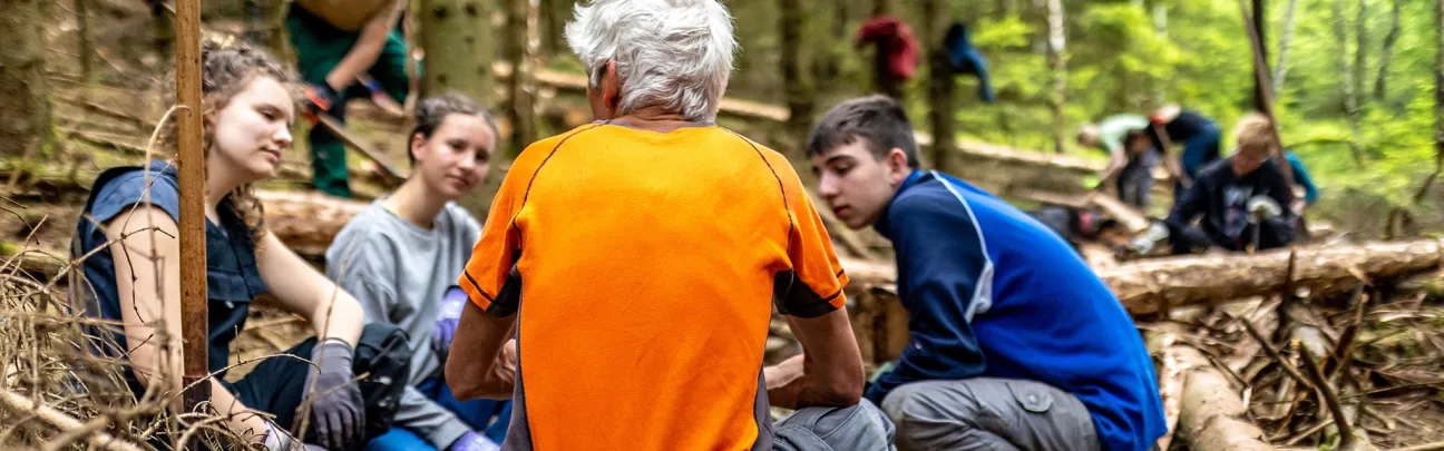 Erklärungen von Projektleiter an Jugendliche zur Borkenkäferbekämpfung