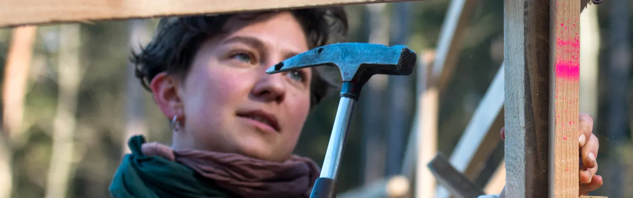 Junge Frau mit Hammer beim Bau eines Hordengatters