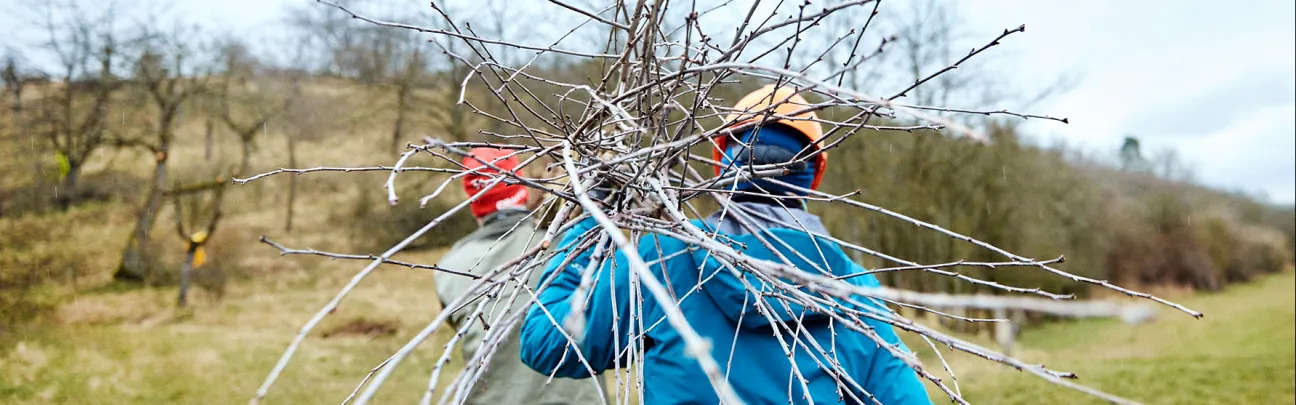 Teilnehmerin von hinten mit Ästen auf der Schulter