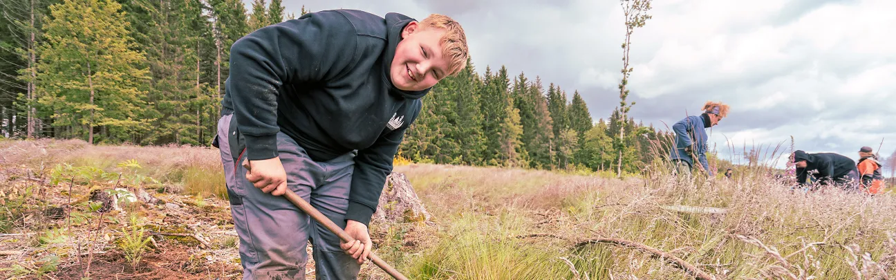 Junger Teilnehmer lächelnd beim Pflanzen