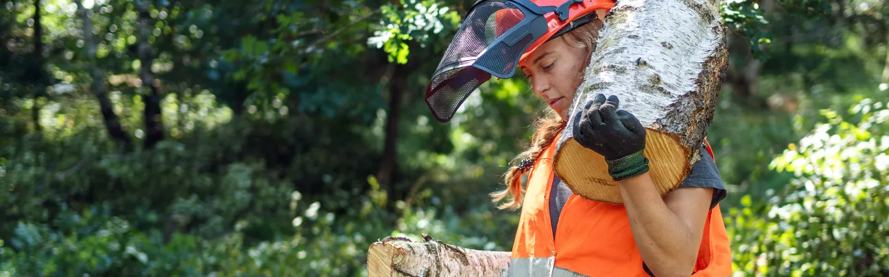 Junge Frau transportiert einen Baumstamm auf ihren Schultern