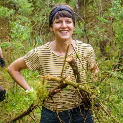 Lächelnde junge Frau, die Äste wegträgt