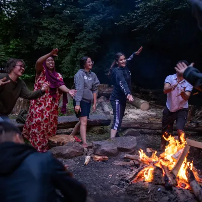 diverse Menschen tanzen ums Feuer
