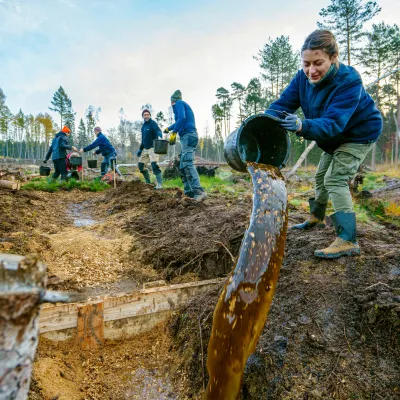Teilnehmerin schüttet Wasser aus einem Eimer