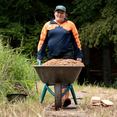 Lächelnde Teilnehmerin schiebt eine Schubkarre mit Erde