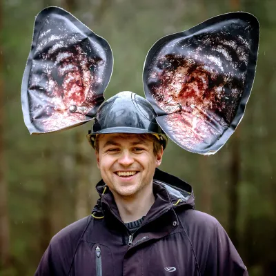 Lachender Teilnehmer mit einem Hut mit Fledermausohren auf dem Kopf