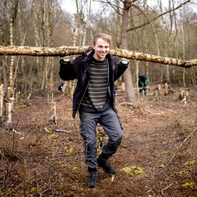 Teilnehmer trägt einen abgesägten Stamm weg