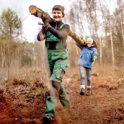Zwei Teilnehmerinnen tragen gemeinsam einen abgesägten Ast weg