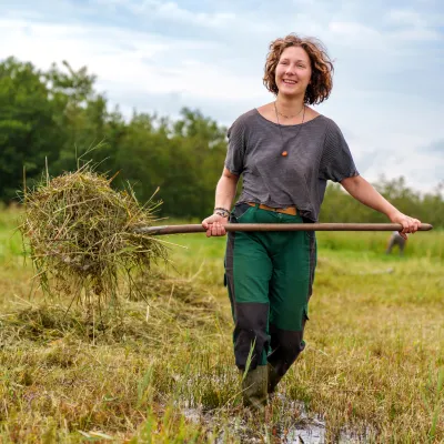 Frau mit Heugabel bei der Mahd