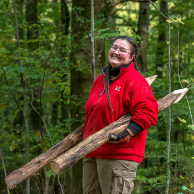 Lachende junge Frau mit zwei angespitzen Baumstämmen
