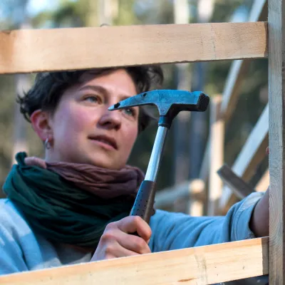 Junge Frau mit Hammer beim Bau eines Hordengatters