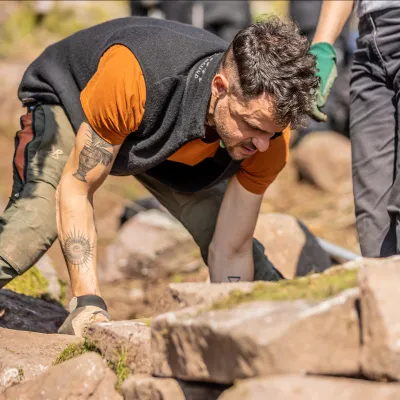 Mann baut Trocksteinmauer