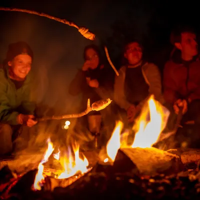 Gruppe ums Feuer mit Stockbrot
