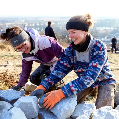Zwei lächelnde Teilnehmerinnen beim Errichten der Steinmauer