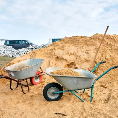 Schubkarren vor einem Sandhaufen