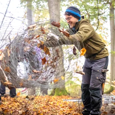 Junger Teilnehmer rollt abgebauten Zaun zusammen