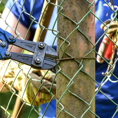 Nahaufnahme einer Zange und eines Maschendrahtzauns