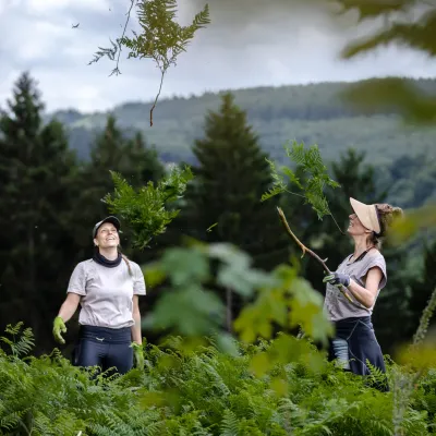 Zwei Teilnehmerinnen werfen Farn in die Luft