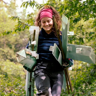 Teilnehmerin trägt lächelnd die Hüllen zum Schutz vor Verbiss