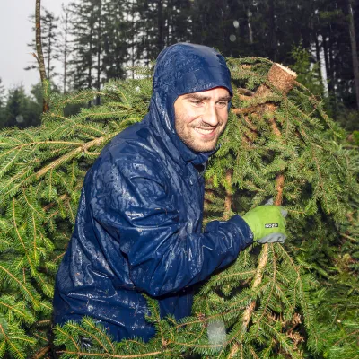 Lächelnder Teilnehmer mit Regenjacke beim Abtransport von Zweigen