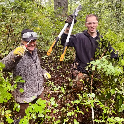 zwei Personen mit Werkzeug im Wald