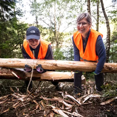 Lächelnde Teilnehmende mit geschälten Baumstämmen