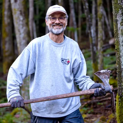 Lächelnder Teilnehmer mit Wiedehopfhaue in den Händen
