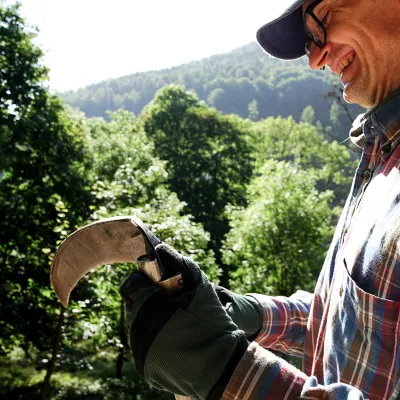Lächelnder Teilnehmer beim Schärfen seiner Sense