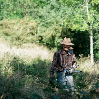 Lächelnder Teilnehmer mit Strohhut und Astschere
