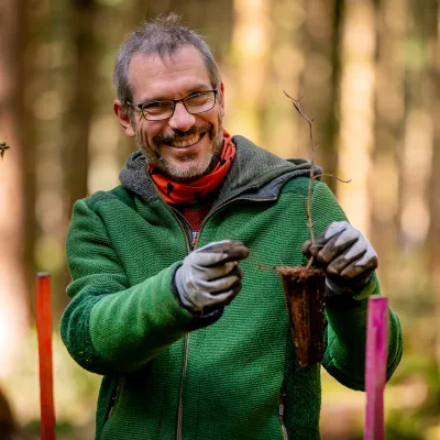 Lächelnder Teilnehmer mit Jungpflanze in der Hand
