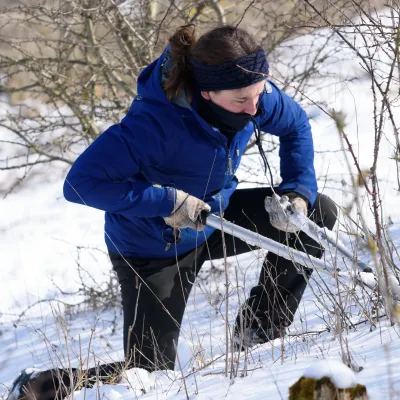 Frau mit Astschere im Schnee