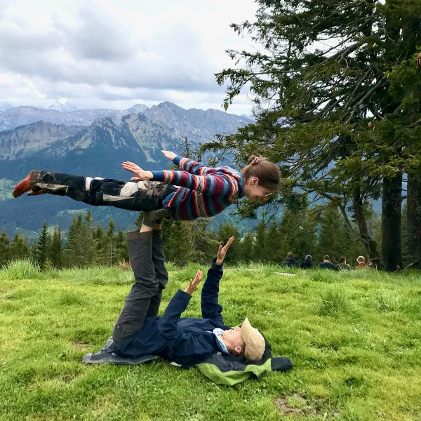Eine junge Frau macht eine Hebefigur auf den gestreckten Beinen eines jungen Mannes