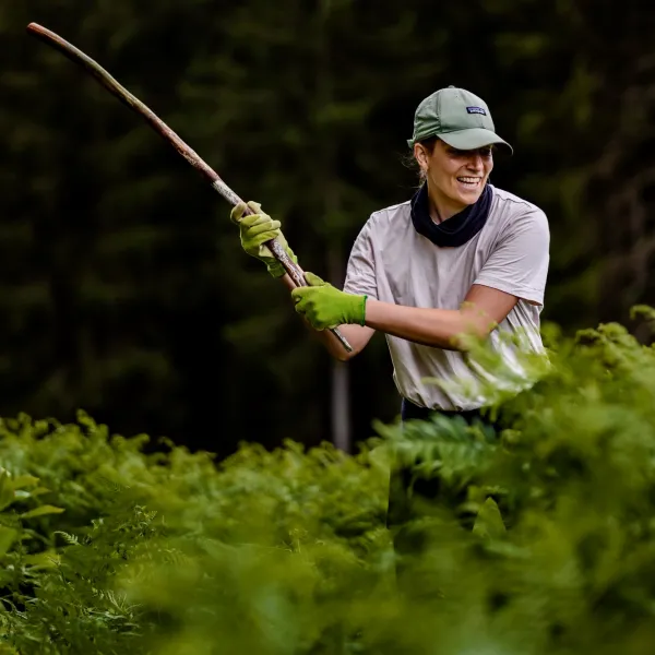 Frau holt mit einem langen Ast zum Schlag aus