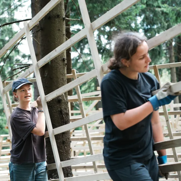 zwei Personen tragen ein Hordengatter im Wald