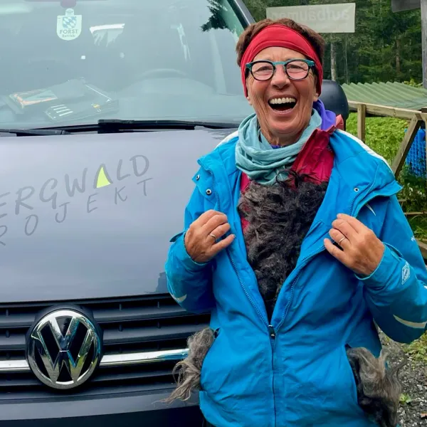 Eine Frau öffnet den Reisverschluss ihrer Regenjacke, aus der Schafwolle quillt