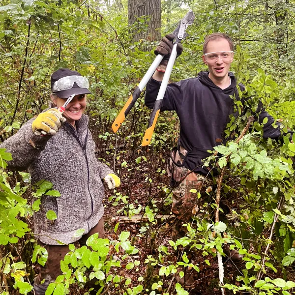 zwei Personen mit Werkzeug im Wald