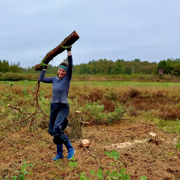 Eine stemmt einen Holzstamm in die Luft
