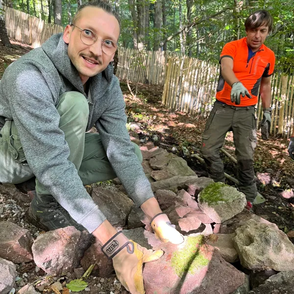 Person baut Trockensteinmauer
