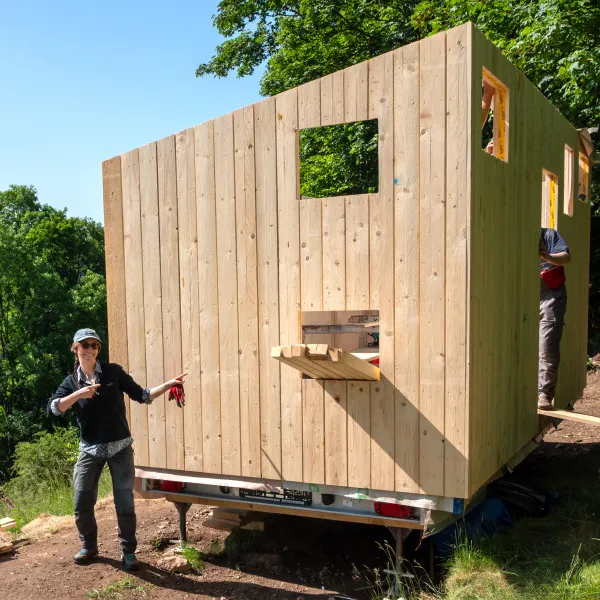 Person steht vor einem Bauwagen